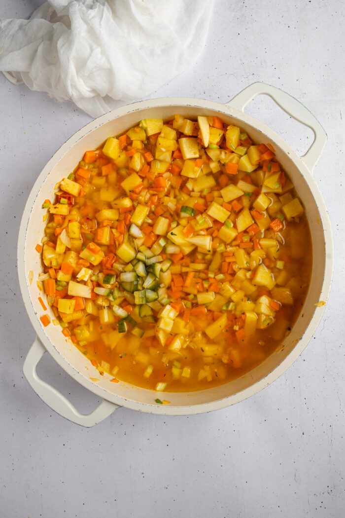 Broth, pickles, and other seasonings added for the creamy dill pickle soup to simmer.