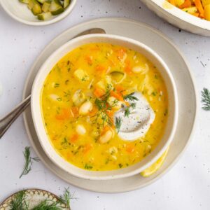 A serving of creamy dill pickle soup with vegan sour cream and extra fresh dill.