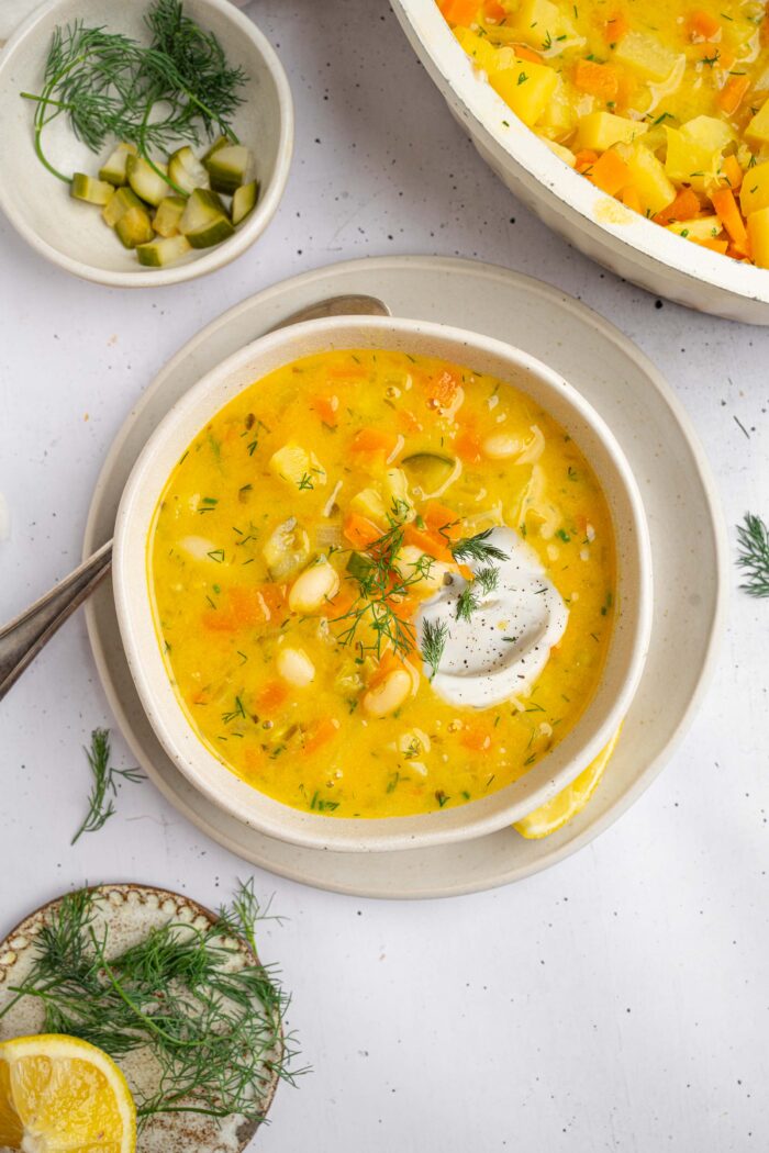 A serving of creamy dill pickle soup with vegan sour cream and extra fresh dill.