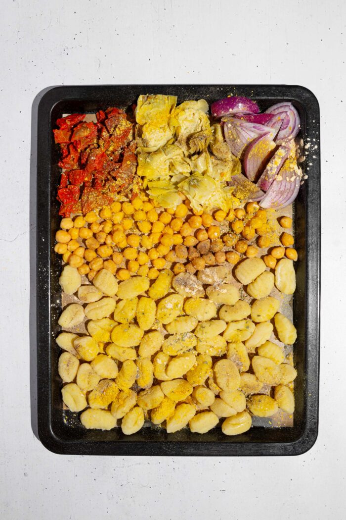 Gnocchi, chickpas, and veggies laid out on a lined baking sheet.