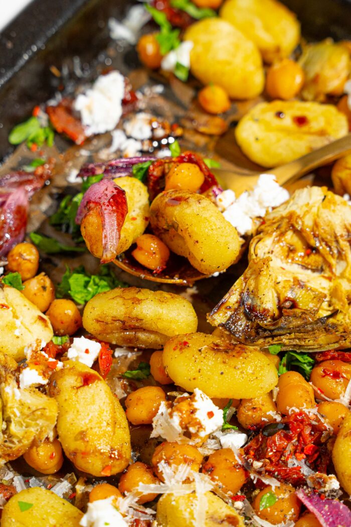 A close shot of a spoon picking up some mediterranean gnocchi.