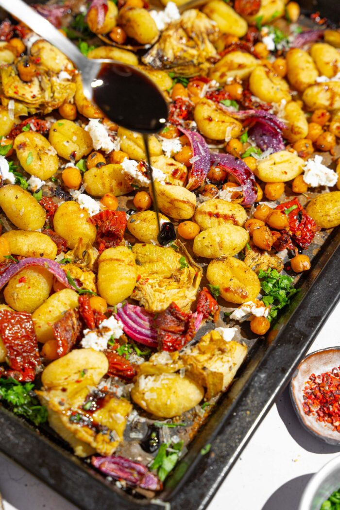 Balsamic glaze being drizzled on top of a mediterranean gnocchi dish.