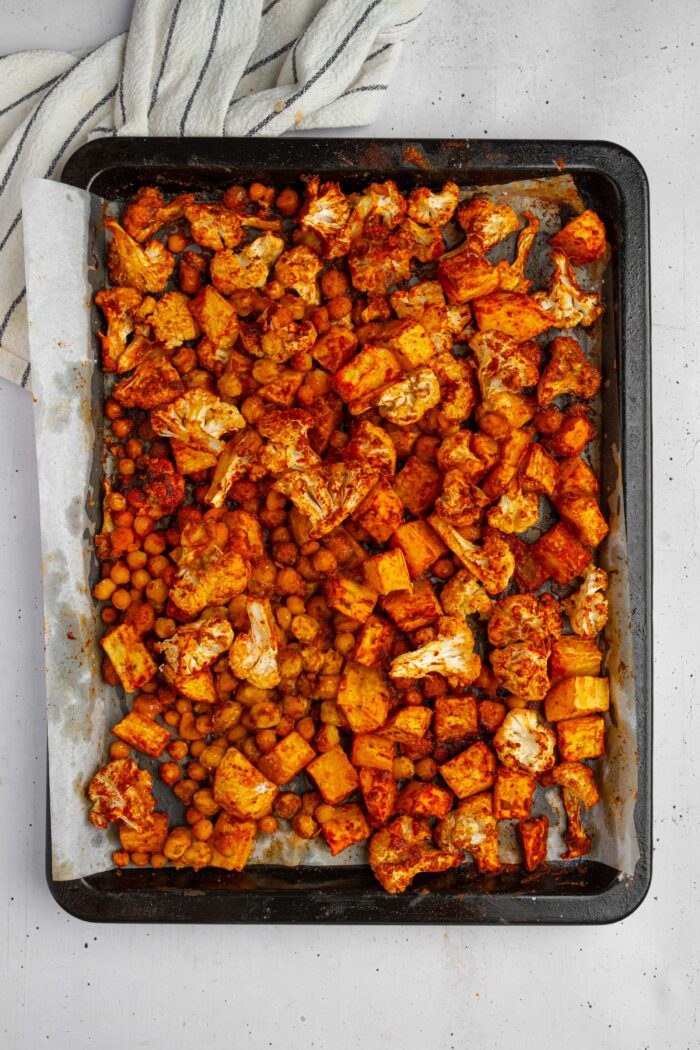 Vegetables and chickpeas roasted together with spices on a sheet pan.