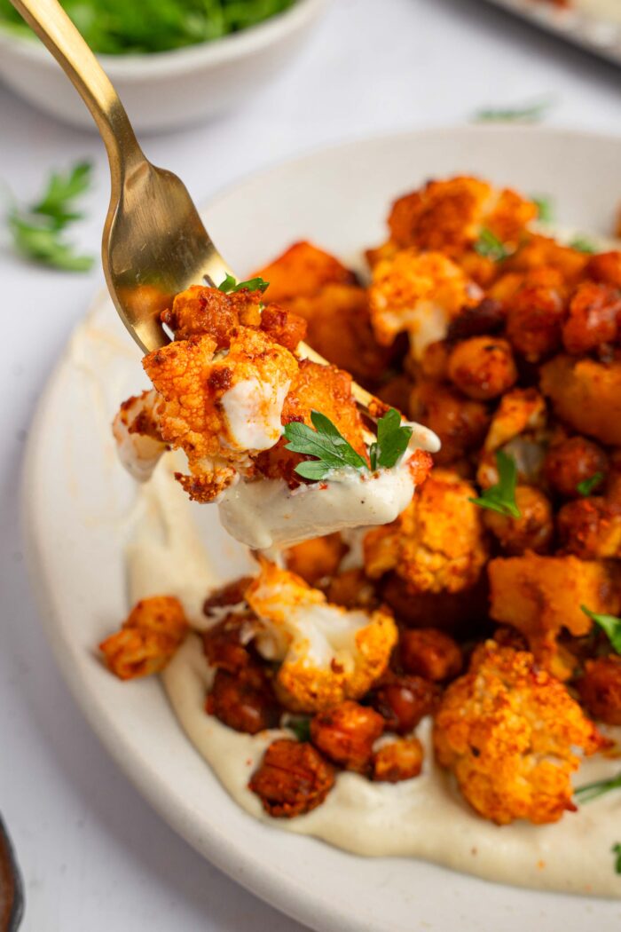 A fork full of fall sheet pan dinner at the forefront, showing off the vibrant ingredients.