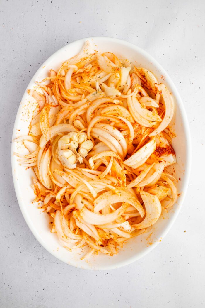 Onions mixed together with spices, and garlic added to the casserole dish.
