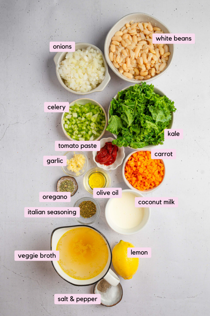 White bean kale soup ingredients laid out and labeled on a light background.
