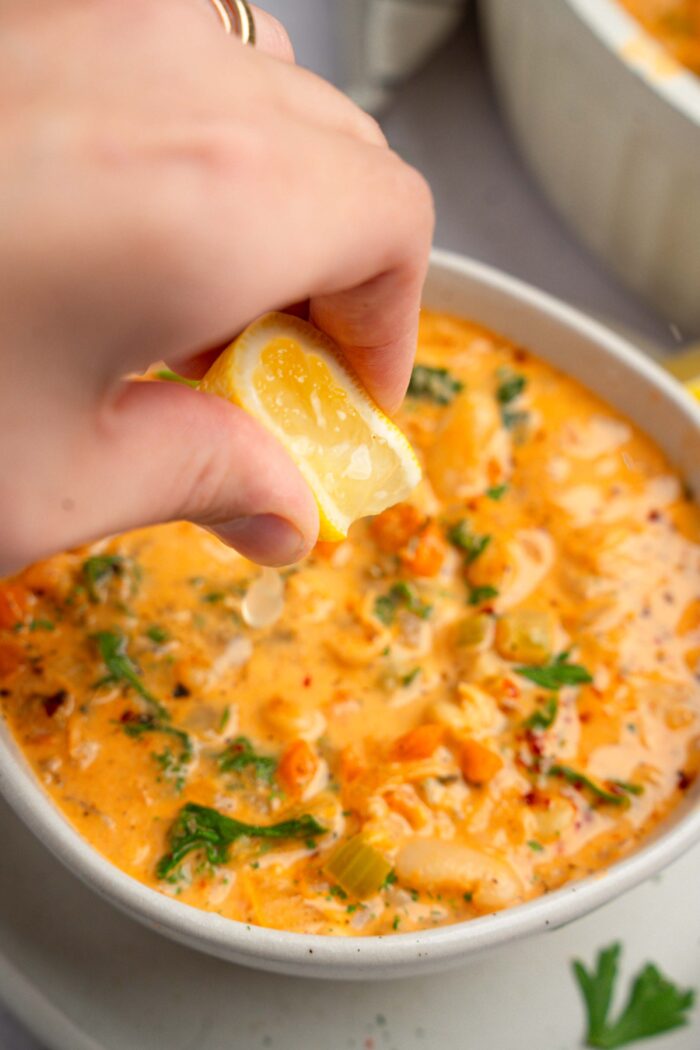 Lemon juice squeezed to serve white bean kale soup.