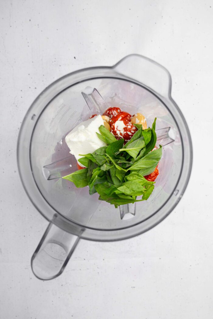 Roasted veggies in a blender, along with fresh herbs and silken tofu.