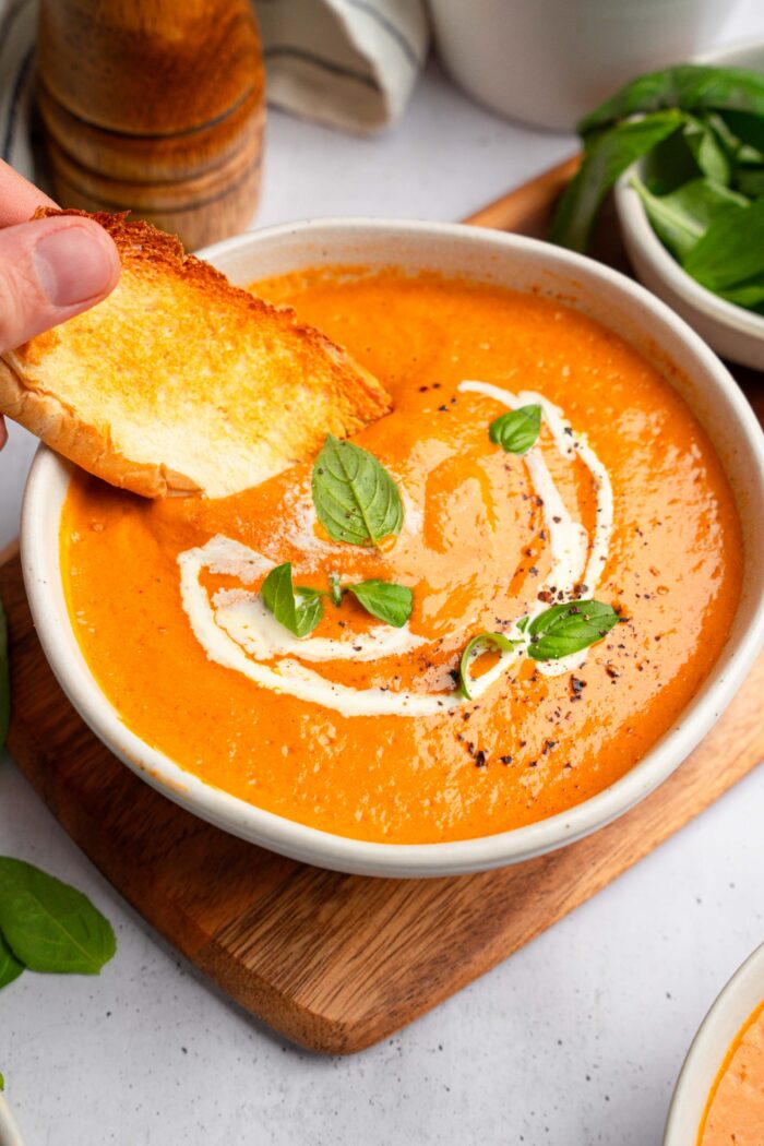Crusty bread being dipped into vegan high protein soup.
