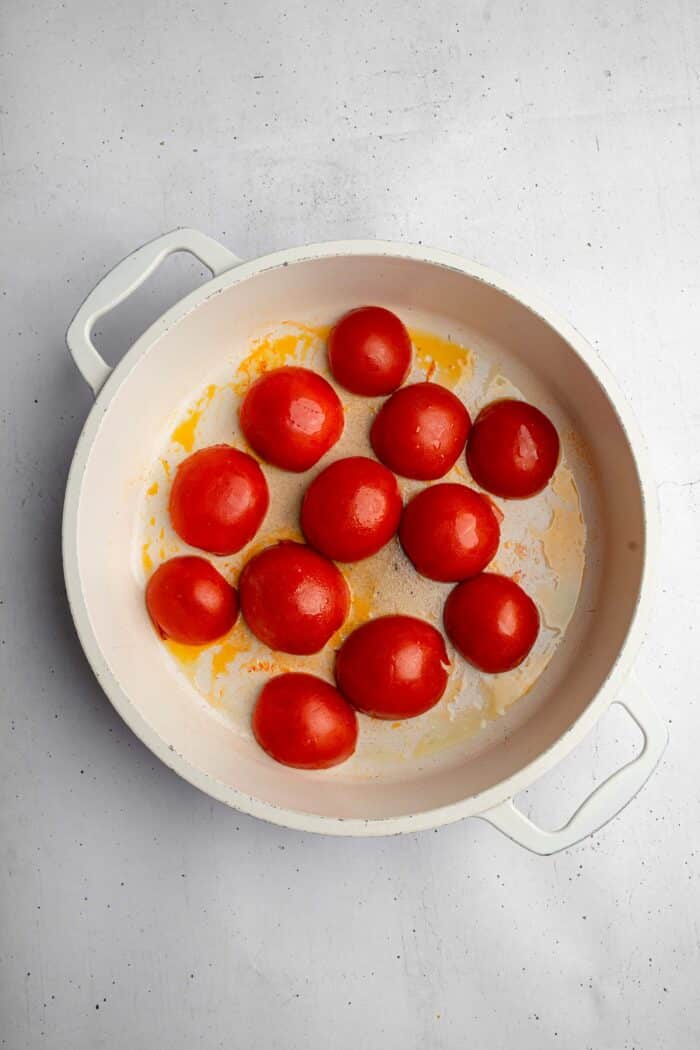 Roma tomatoes, cut in half and cooking on the frying pan, cut side down.