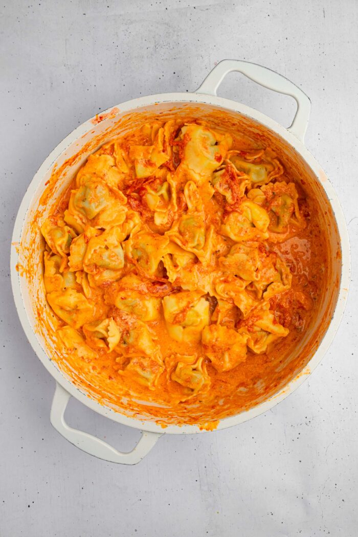 Tortellini mixed together with the sauce in a pan.