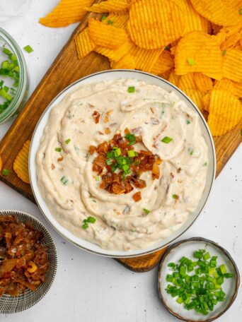 Caramelized Onion Dip served with more onions, fresh chives, and chips for dipping.