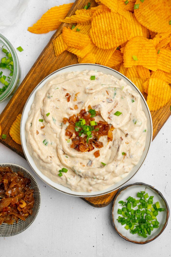 Caramelized Onion Dip served with more onions, fresh chives, and chips for dipping.