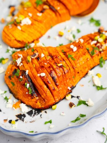 A closer shot of one butternut squash half, served with vegan feta, pistachios and parsley.