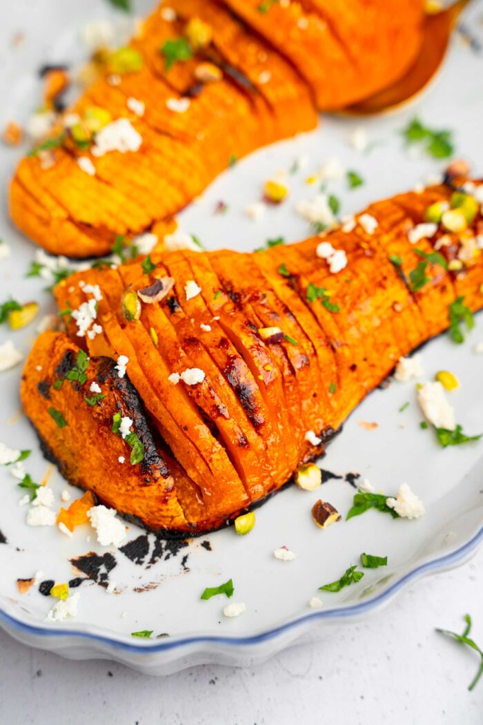 A closer shot of one butternut squash half, served with vegan feta, pistachios and parsley.