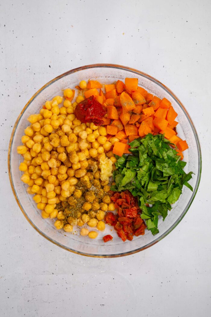 Veggies, chickpeas, and seasonings in a large round casserole dish.