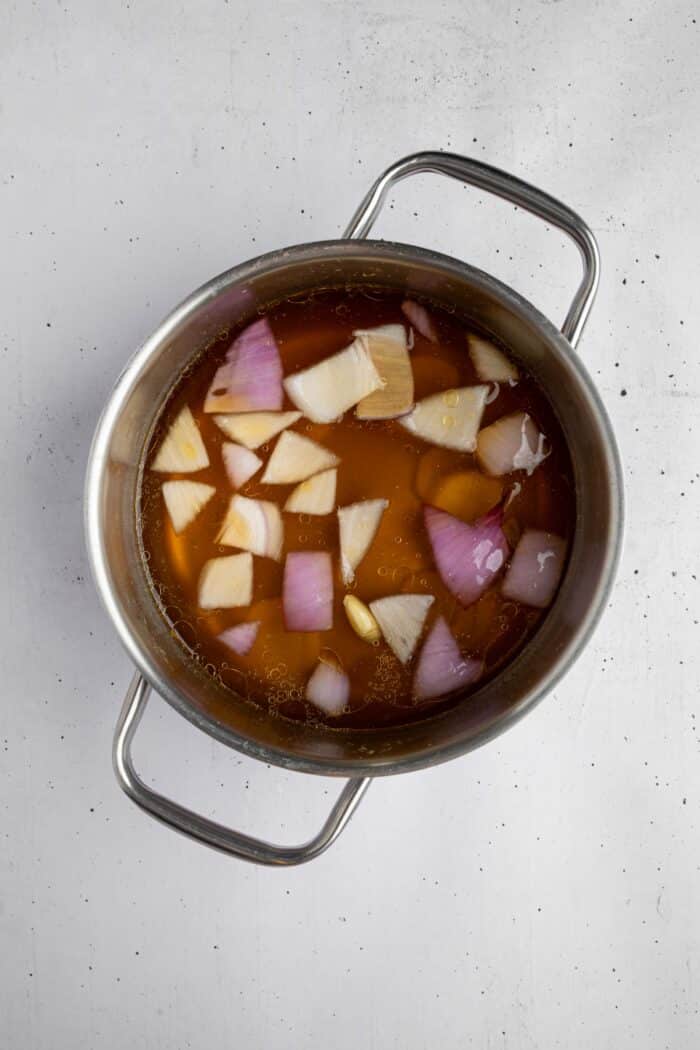 Ginger, onion, and garlic simmering in vegetable broth to infuse it.