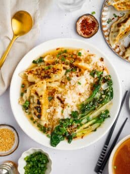 A title image showing steamed rice, sauteed bok choy and fried dumplings served with aromatic broth in a white ceramic bowl.