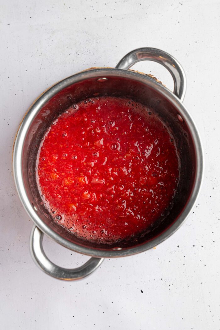 Easy berry compote in a steel saucepan, made with fresh raspberries.
