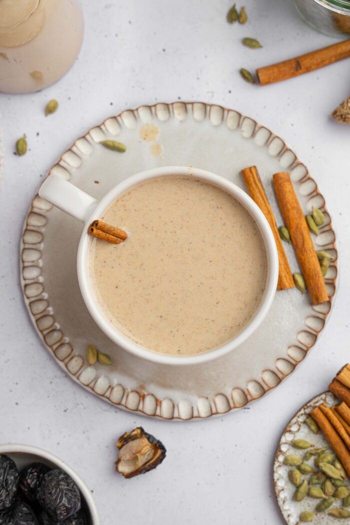 Top down view of warm date milk served with cinnamon sticks.