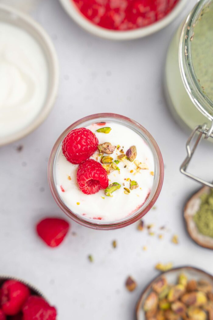 Matcha Chia pudding photographed from above, with pistachios and fresh raspberries as a topping.