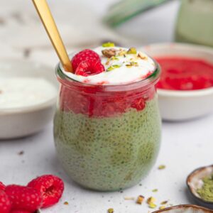 Matcha chia pudding served with vegan yogurt and toppings, with a spoon sticking out.