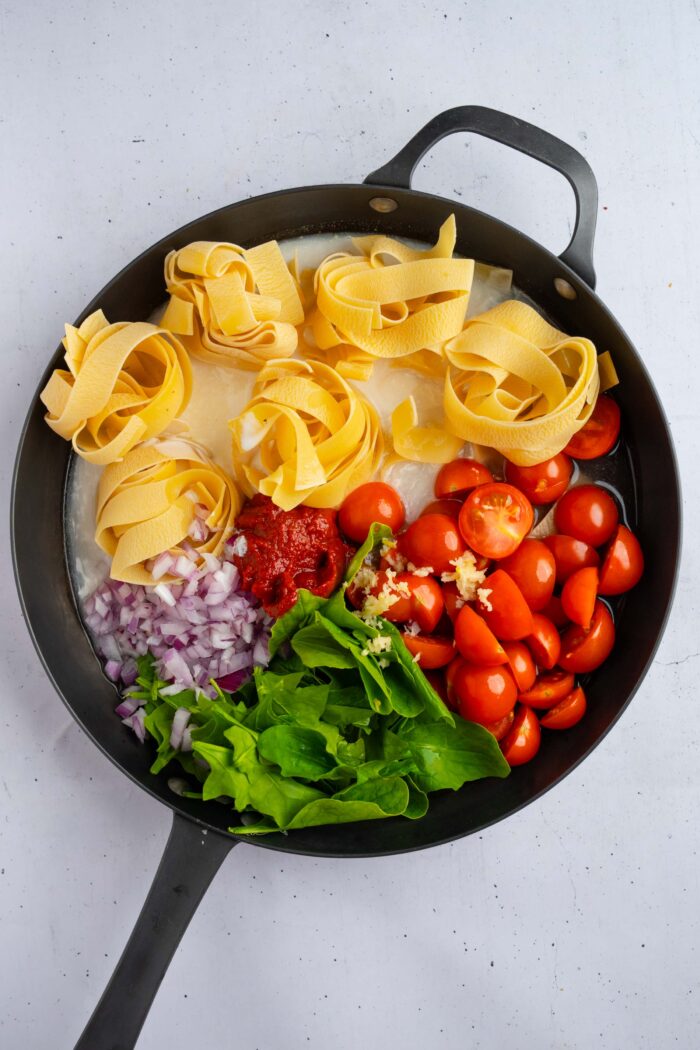 All of te ingredients for one pot creamy pasta combined in a large skillet.