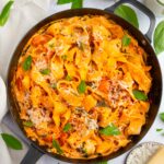 One pot creamy vegan pasta in a large skillet, with vegan parmesan and fresh basil as garnish.