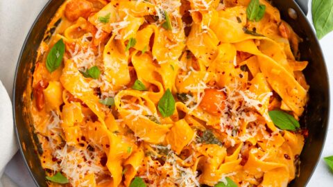 One pot creamy vegan pasta in a large skillet, with vegan parmesan and fresh basil as garnish.