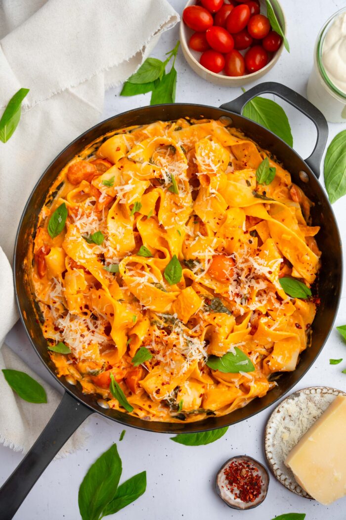 One pot creamy vegan pasta in a large skillet, with vegan parmesan and fresh basil as garnish.