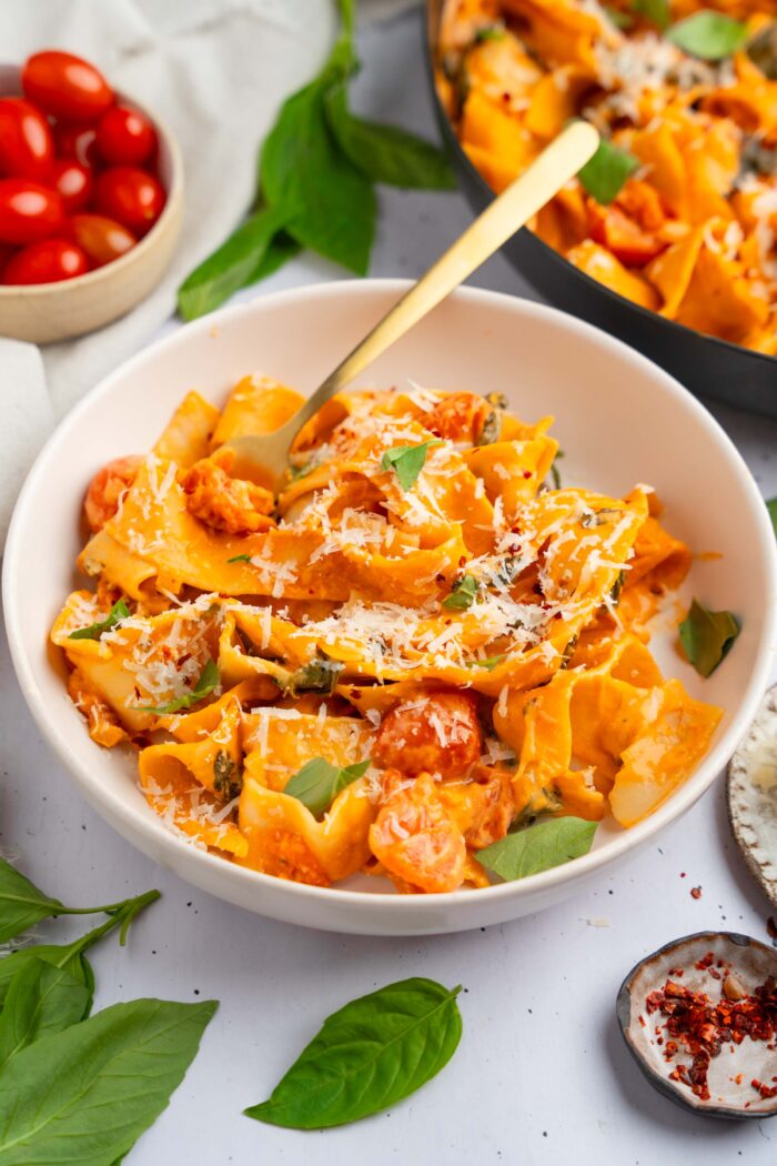 A serving of one pot creamy pasta with vegan parmesan and fresh herbs.