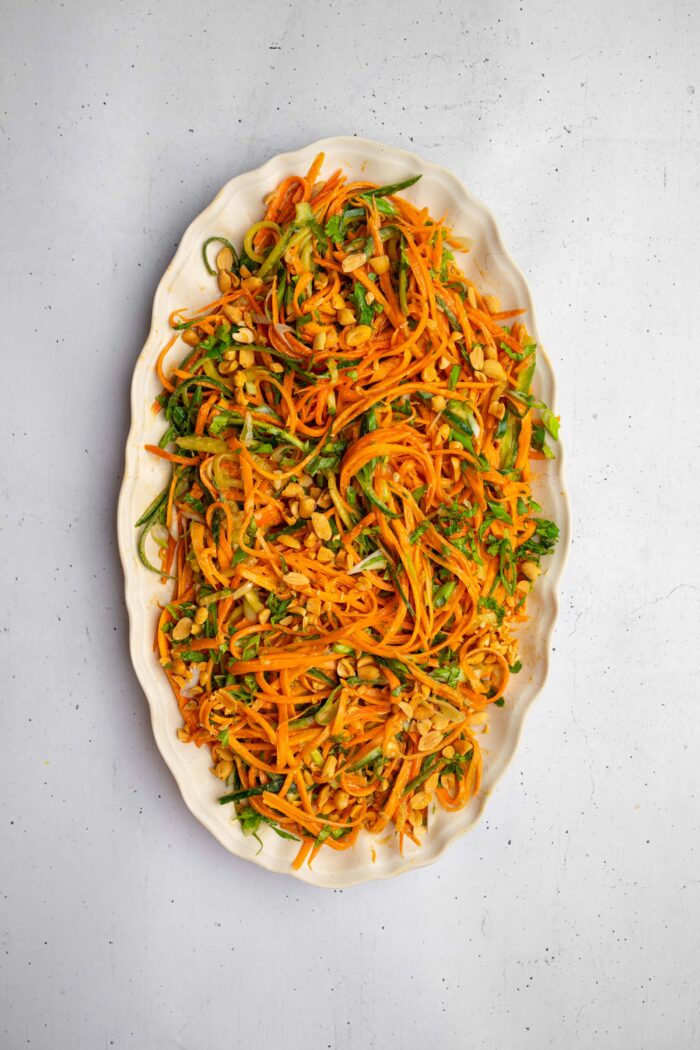 After everything is mixed together, the carrot and cucumber salad is served on a large oval platter with extra peanuts.