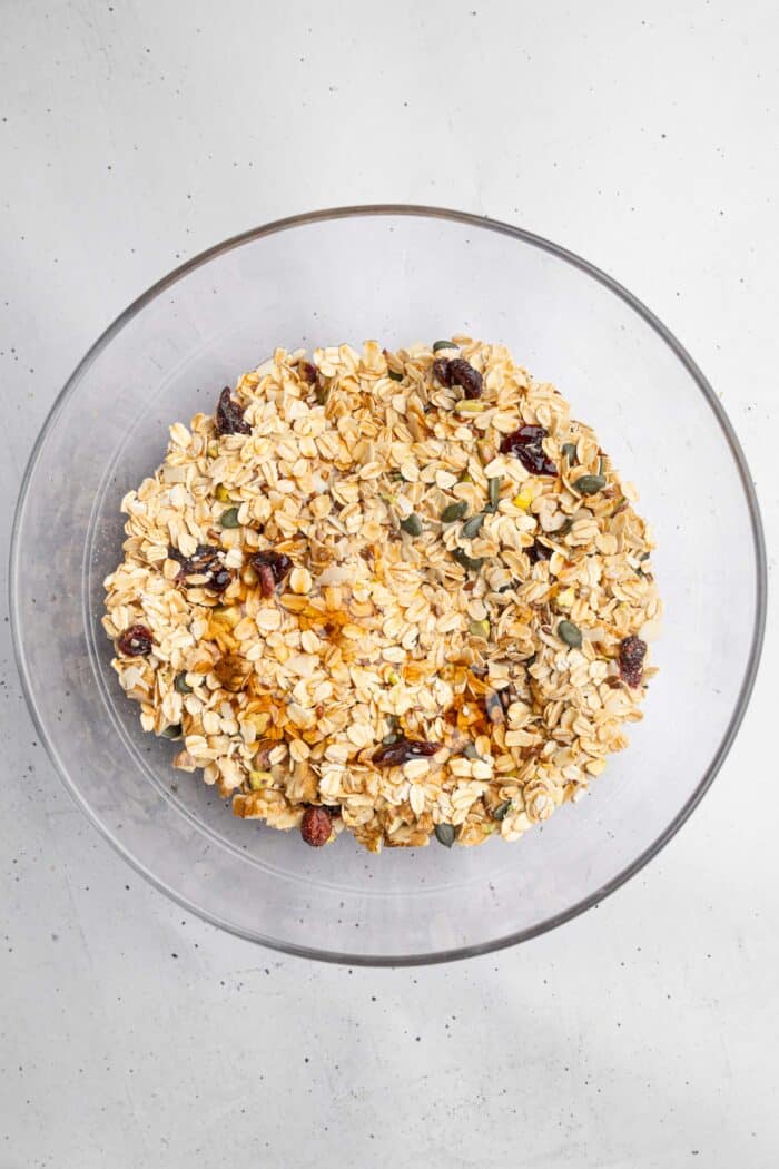 A mixture of oats, nuts, seeds, and dried fruit with coconut oil and maple syrup.