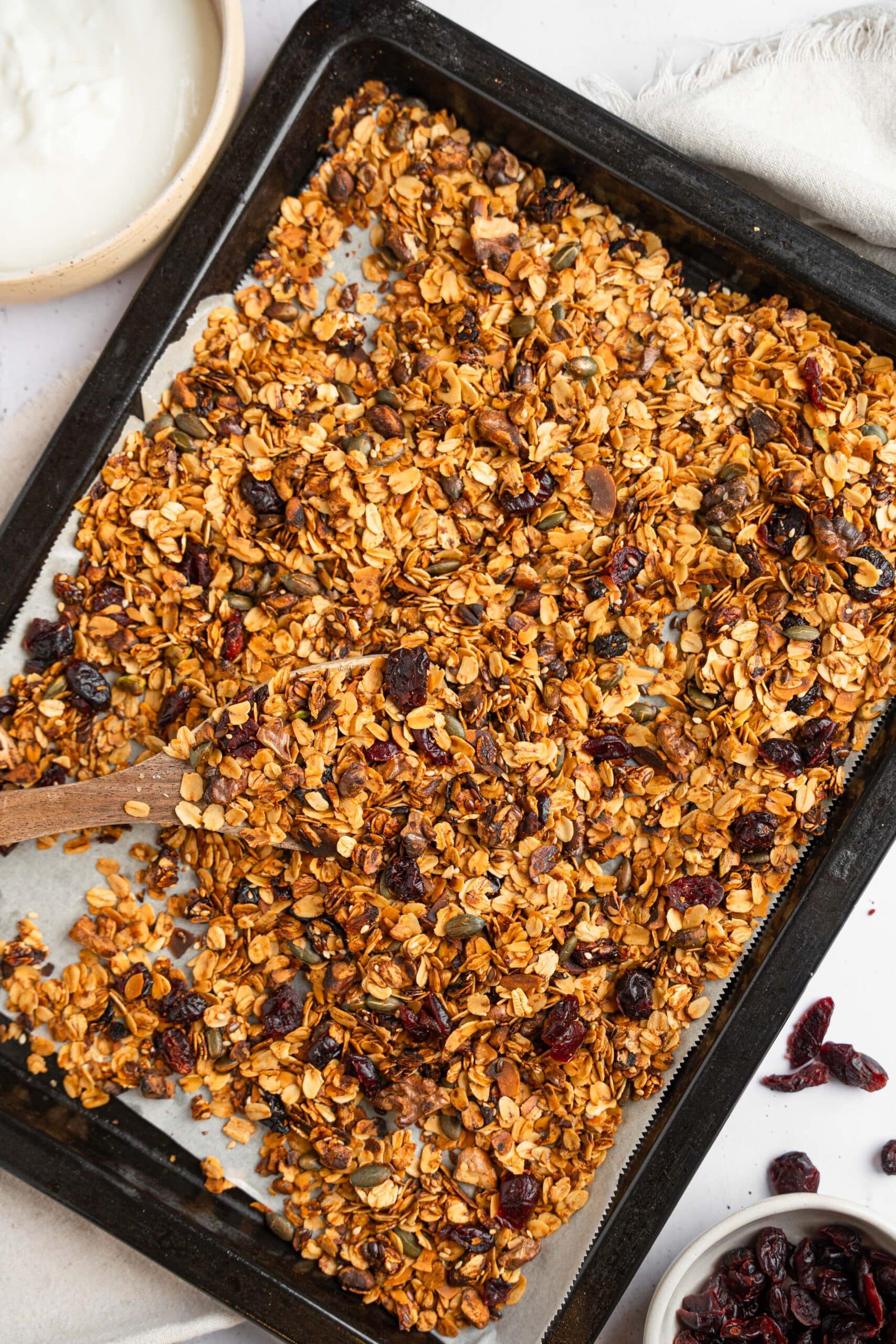 Homemade granola spread across a baking sheet lined with parchment.