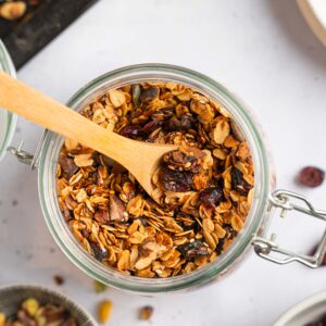 Top down image of a mason jar filled with air fryer granola, with a wooden spoon sticking out.