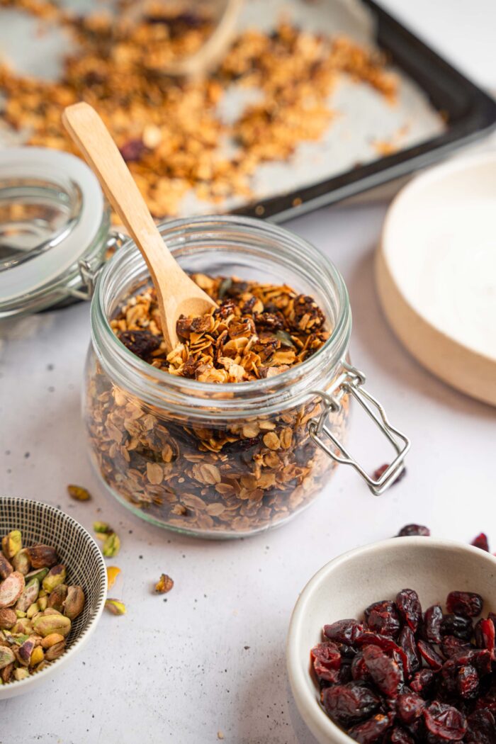 Air fryer granola in a mason jar, with a wooden spoon sticking out.
