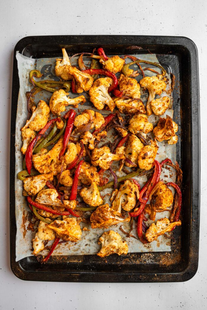 Cooked mixture of cauliflower, bell peppers, and red onion, mixed with spices.