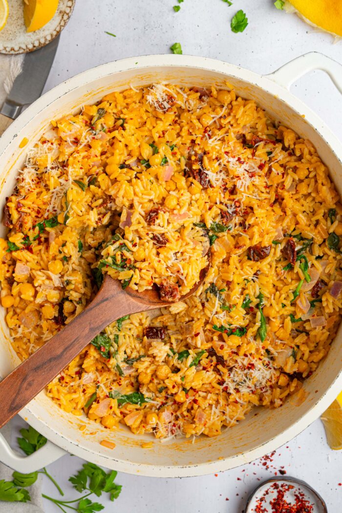 A white pan with marry me orzo and a wooden serving spoon sticking out.