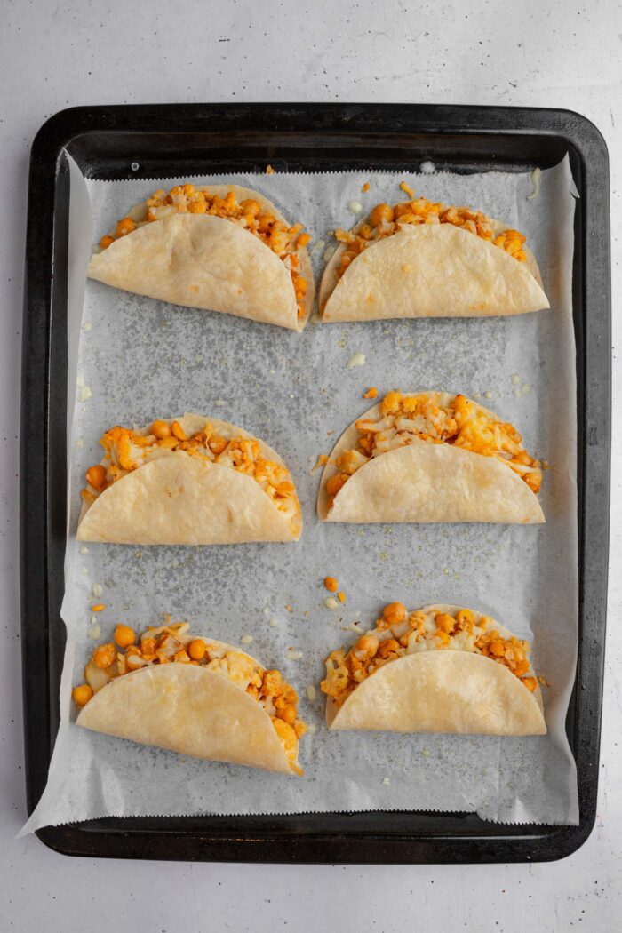 Small tortillas folded over the folling to make oven baked buffalo chickpea cauliflower tacos.