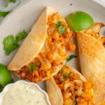 A close up of buffalo chickpea cauliflower tacos served with vegan caesar dressing.