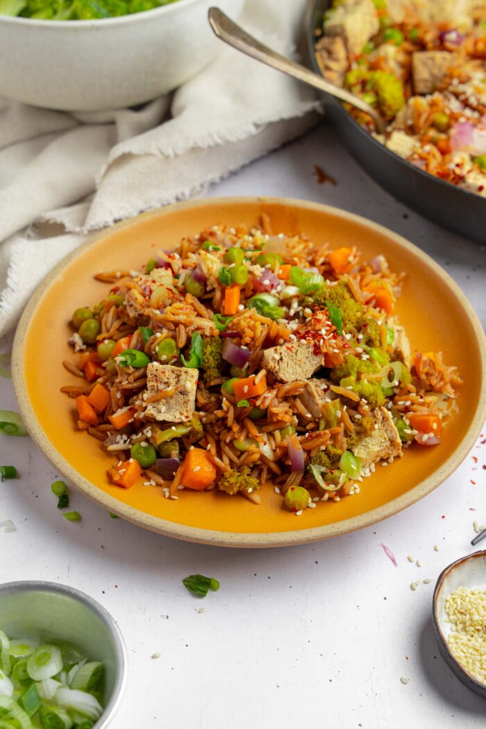 A plate of one pot veggie rice with spring onions and sesame seeds on top.