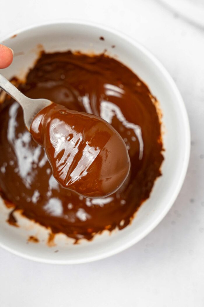 A fork holding the peanut butter "egg" freshly dipped in melted chocolate.