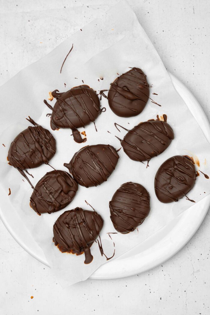 Nine chocolate peanut butter Easter eggs laid out on parchment and drizzled with dark chocolate.