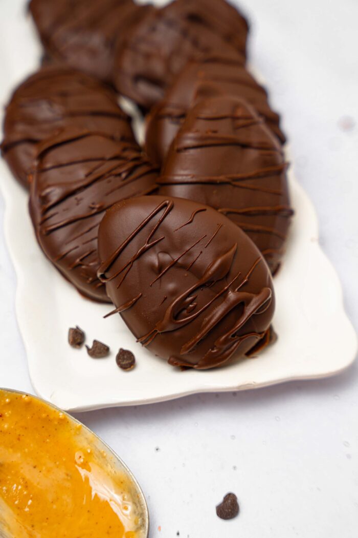 A close up shot of chocolate peanut butter Easter eggs , with a few chocolate chips on the plate.