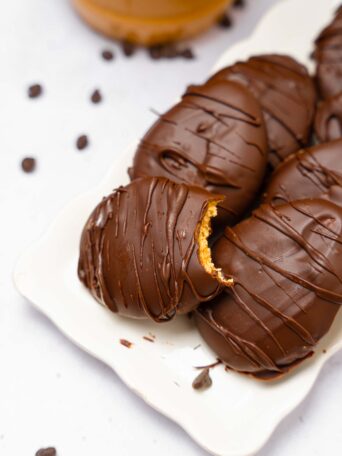 A platter of chocolate peanut butter Easter eggs with a bite taken out of the first one.