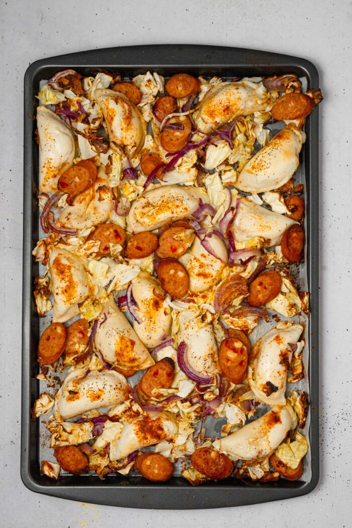 Vegetables, vegan sausage, and pierogies mixed together in the sheet pan after cooking.