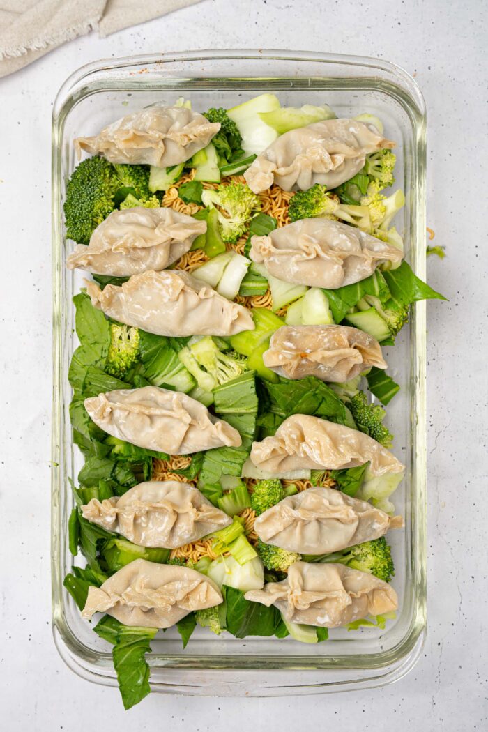Dumplings added on top of the ramen and bok choy in the baking dish.