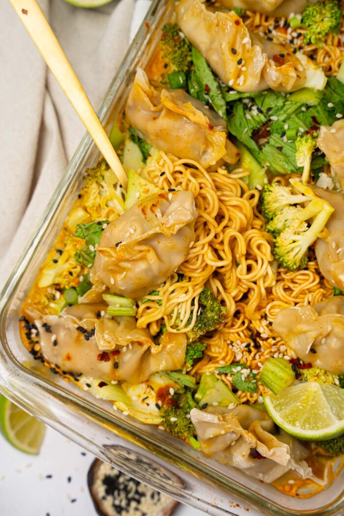A utensil scooping some of the dumpling bake with noodles out of the baking dish.