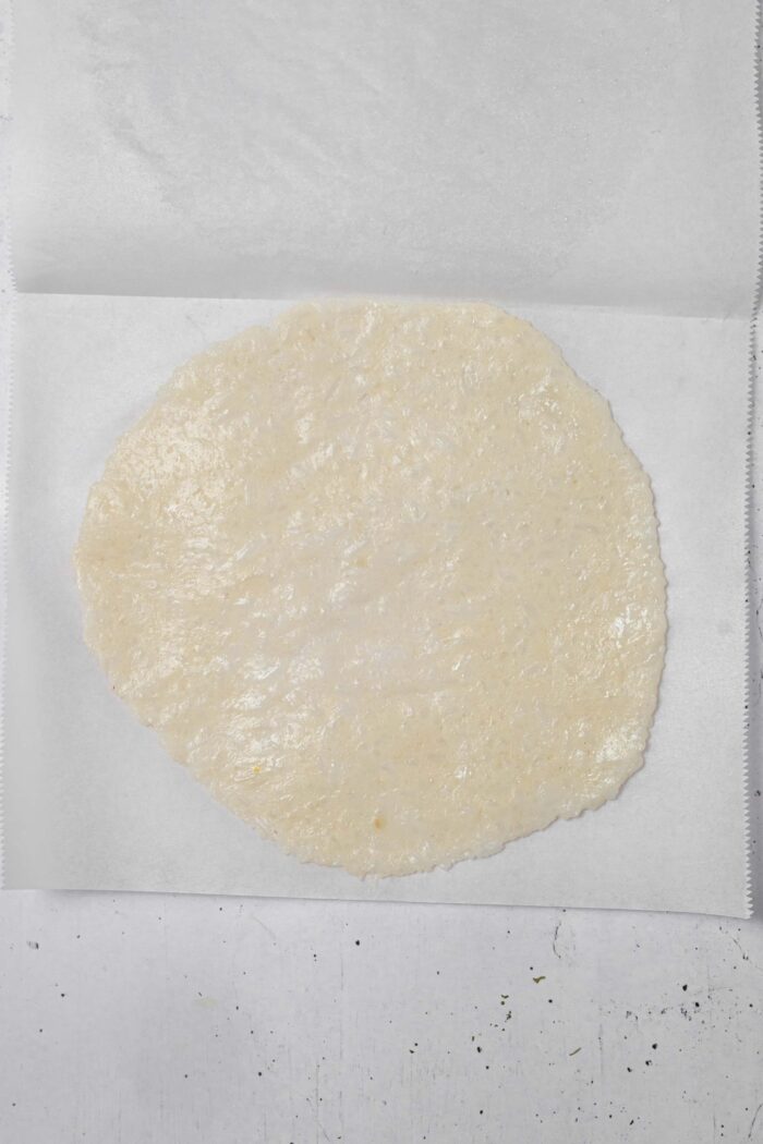 After pressing between two sheets of parchment paper, the rice tortilla is ready to cook.