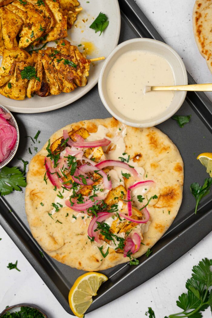 A serving of tofu skewers in a naan, with the rest of the components on the same baking sheet.